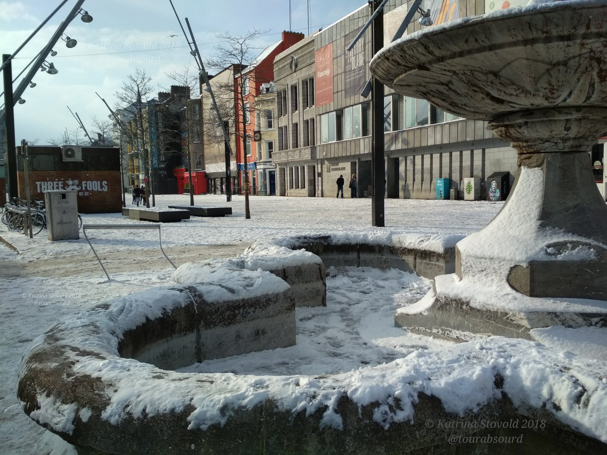 A fountain on Grand Parade street in Cork, Ireland, with snow on the ground and the edges of the fountain.